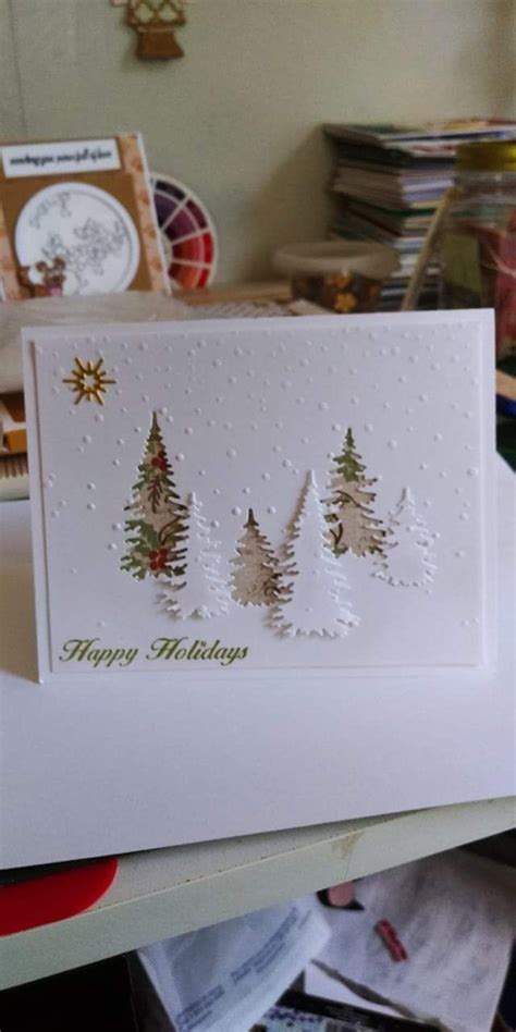 Three Christmas Trees On A Table With Other Cards And Papers In The