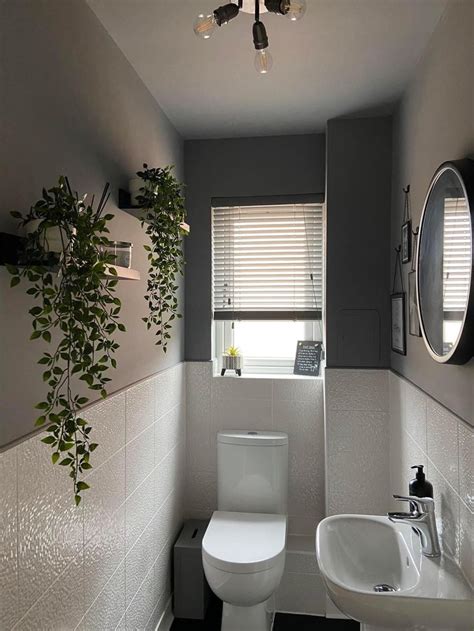 A White Toilet Sitting Next To A Sink In A Bathroom Under A Window With