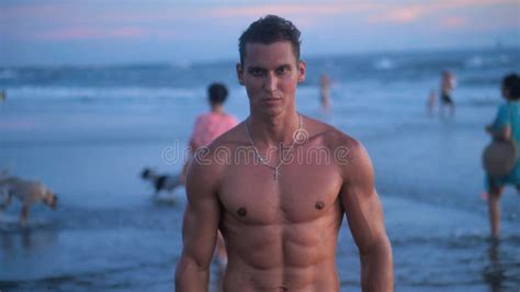 Portrait Of Muscular Man With A Naked Torso On The Beach At Sunset