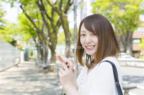 スマホを持つ若い女性 カメラ目線で笑顔 原宿 写真素材 5021007 フォトライブラリー Photolibrary