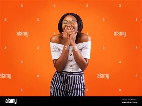 African American Woman Laughing Covering Mouth Standing Over Orange