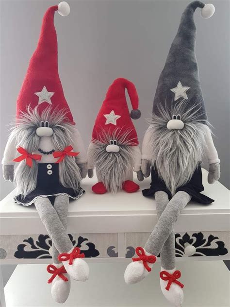 Three Stuffed Gnomes Sitting On Top Of A White Shelf With Red And Gray