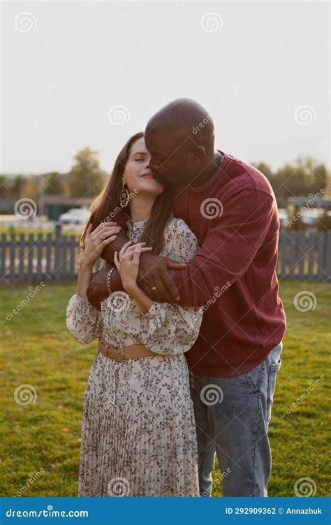 Portrait Of Interracial Couple In Love Gently Hugging And Kissing With Eyes Closed In Nature