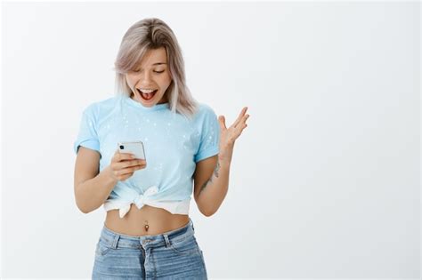 Free Photo Portrait Of Satisfied Blonde Girl Posing With Her Phone In The Studio