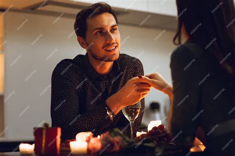 집에서 낭만적 인 촛불 저녁 식사를하는 아름다운 열정적 인 커플 남자 키스 손 프리미엄 사진