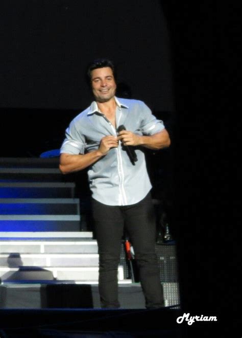 A Man Standing On Stage With His Hands In His Pockets