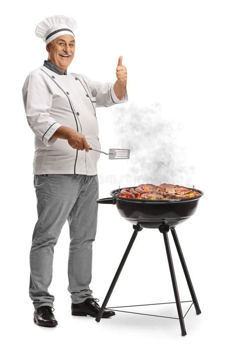 Mature Male Chef Grilling Meat On A Bbq And Gesturing Thumbs Up Stock