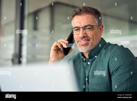 Busy Older Business Man Making Phone Call Using Laptop Computer In