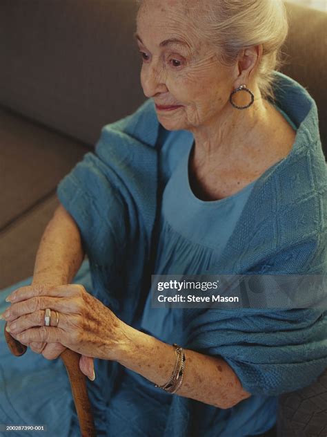 Senior Woman Holding Walking Stick Sitting Indoors Closeup Elevated