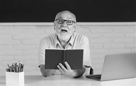 Portrait Of Mature Teacher Or Tutor Professor Working At Table In College Or High School Senior