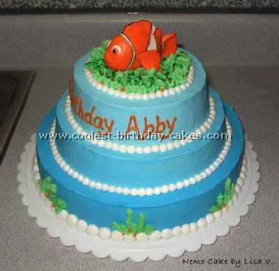 A Three Tiered Blue Cake With An Orange Fish On Top And Seaweed Around