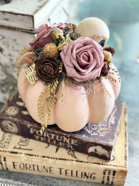 A White Pumpkin Decorated With Flowers And Leaves On Top Of A Stack Of