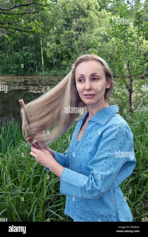 Beautiful Woman Combs Long Hair In The Summer Day On The River Bank