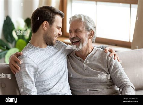Smiling Mature Dad And Grownup Son Relax Together At Home Stock Photo