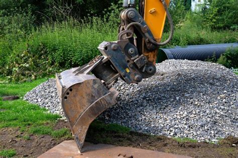 Premium Photo Excavator Bucket Poised Over A Pile Of Gravel A Black