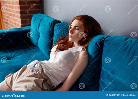 Young Redhead Woman Reclining On The Couch And Feels Tired Stock Image