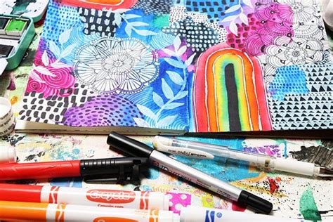 Several Pens Are Laying On Top Of A Colorful Notebook And Some Other