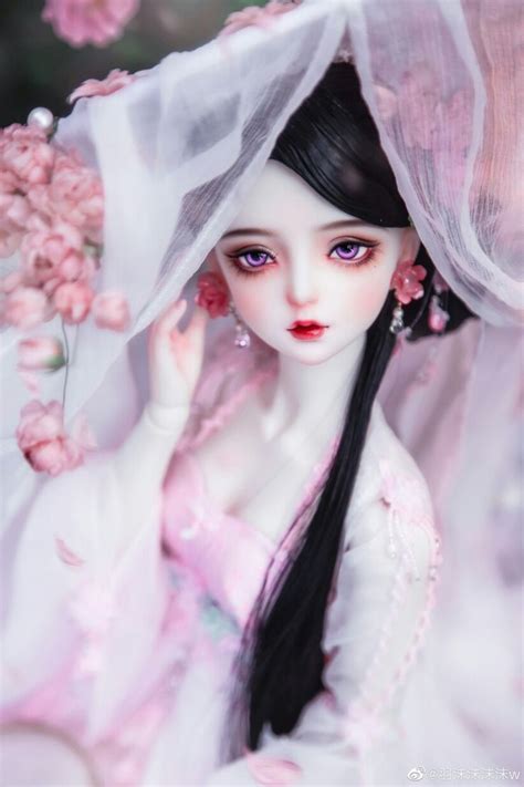 A Doll With Long Black Hair Wearing A White Dress And Pink Flowers In