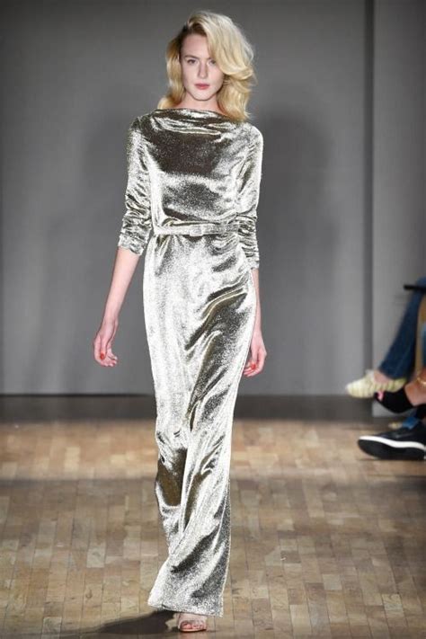 A Model Walks Down The Runway Wearing A Silver Dress With Long Sleeves