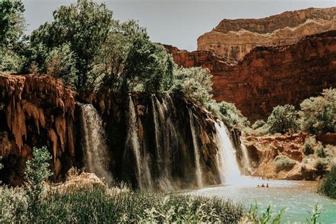 The Waterfall Is Surrounded By Trees And People In Canoes On The River