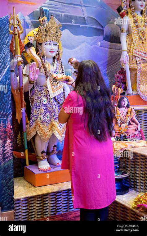 Un hindú adoradora olas una vela delante de una estatua del dios Shiva