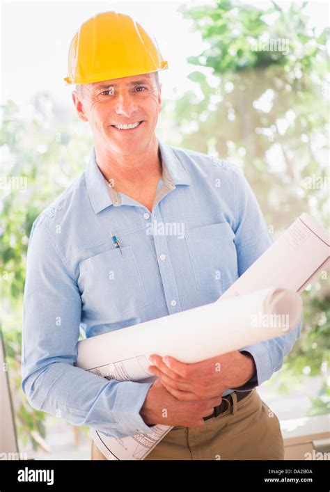 Portrait Of Man In Hardhat Holding Rolled Up Blueprints Stock Photo Alamy