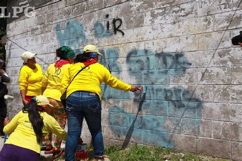 Reclusas borran graffitis de pandillas en una de las zonas más