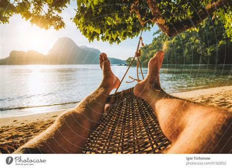 Feet Of Adult Man Relaxing In A Hammock On The Beach During Summer