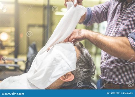 Barber Applying A Hot Towel In A Man Face Before Giving Him A Shave At