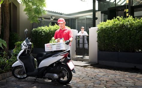 Premium Photo Asian Delivery Man In Red Uniform Delivering Groceries