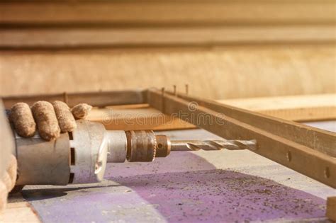 A Man Works With Metal And An Electric Drill Drills Holes In The Metal