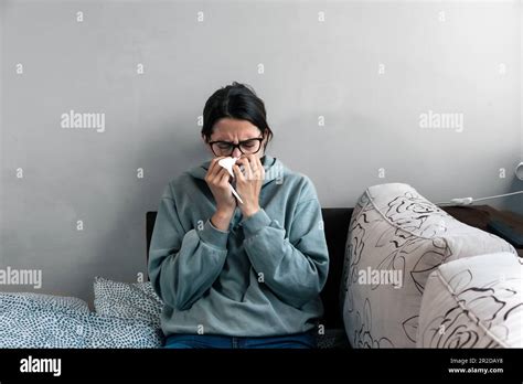 Ill Upset Young Woman Sitting On Sofa Covered With Blanket Freezing