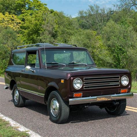 An Old Truck Is Parked On The Side Of The Road In Front Of Some Trees