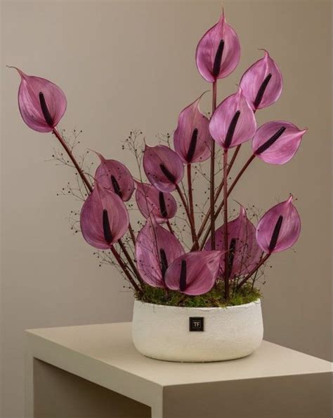 A White Vase Filled With Pink Flowers On Top Of A Table