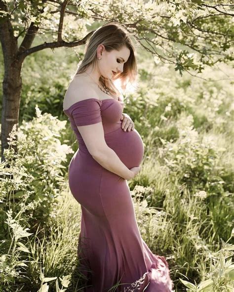 A Pregnant Woman In A Purple Dress Standing Under A Tree