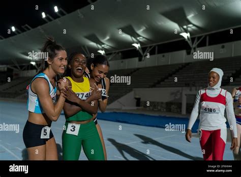 Happy Female Track And Field Athletes Celebrating On Track At Night