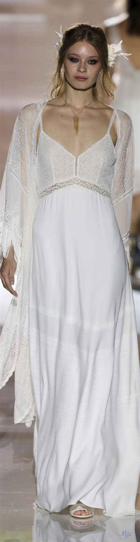 A Woman Walking Down A Runway Wearing A White Dress