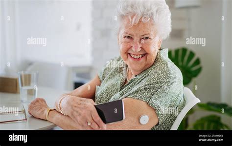 Diabetic Senior Patient Checking Blood Glucose Level At Home Using