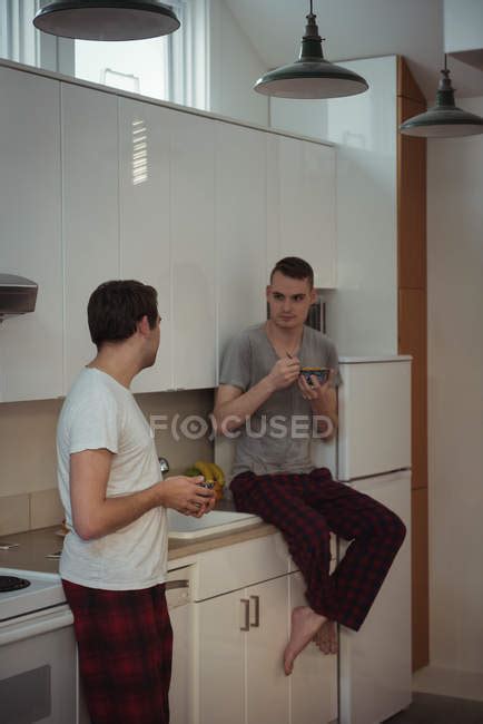 Gay Couple Having Breakfast In Kitchen At Home Talking Stay At Home Stock Photo