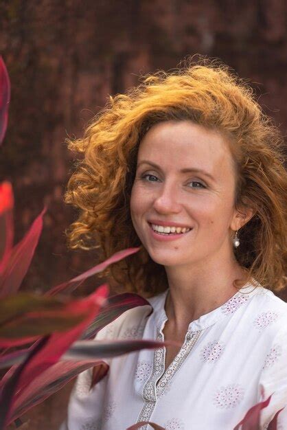 Premium Photo A Woman Smiles In Front Of A Leafy Plant