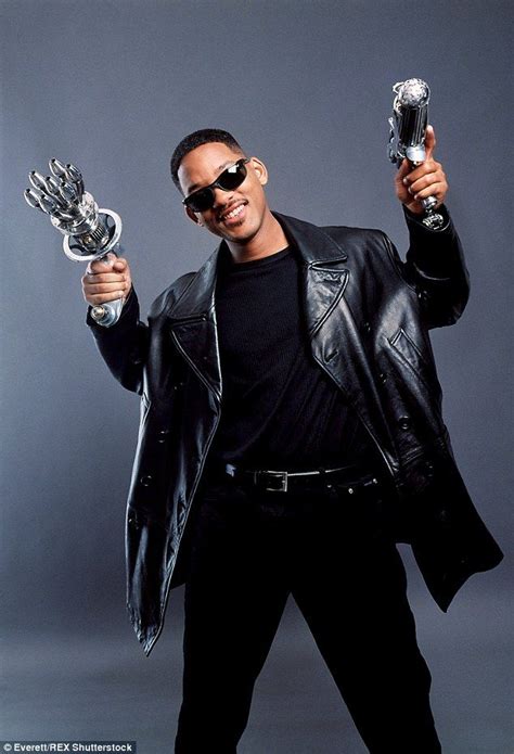 A Man In Black Jacket And Sunglasses Holding Two Silver Objects