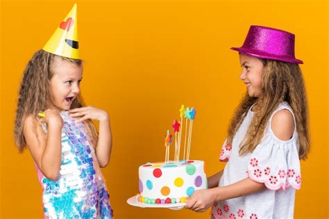 Petite Fille Blonde Surprise Avec Une Casquette De Fête Regardant Une Petite Fille Caucasienne