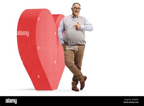 Mature Man Leaning On A Big Red Heart And Pointing Isolated On White