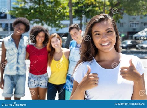 Ragazza Dell America Latina Che Mostra Pollice Con La Multi Gente Etnica Del Gruppo Fotografia