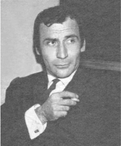 Black And White Photo Of Man In Suit Sitting Down With His Hand On His Chin