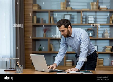 Focused Mature Businessman Reviewing Documents At His Laptop In A Well
