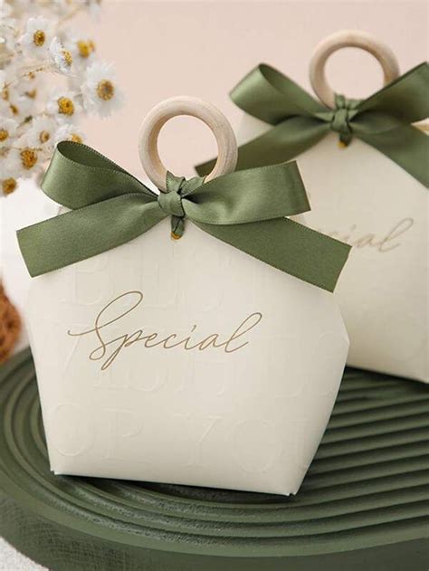 Two Small White Boxes With Green Bows On Them Sitting On A Table Next