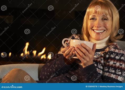 Mature Woman Relaxing In Front Of Fire At Home Stock Photo Image Of