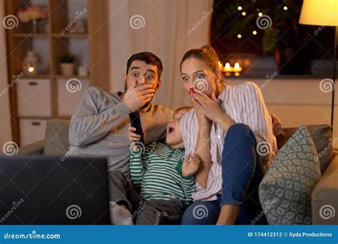 Familia Asustada Viendo La Tele En Casa Por La Noche Foto De Archivo