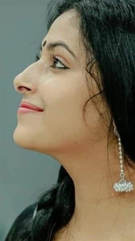 A Close Up Of A Woman With Long Black Hair And Earrings On Her Neck